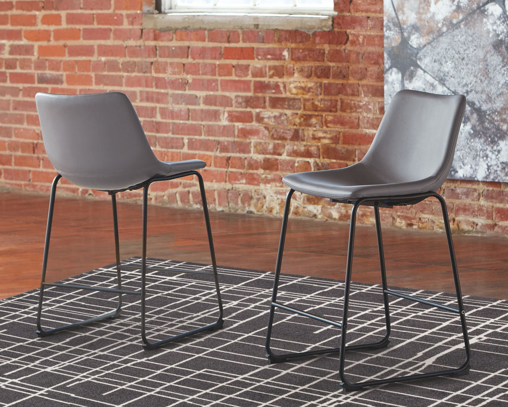 With its distinctive contoured bucket seat and tubular metal base, this bar stool serves up a fresh twist on mid-century inspired style. Chic gray faux leather upholstery adds to the aesthetic. What a timeless look for eat-in kitchens and casually cool di