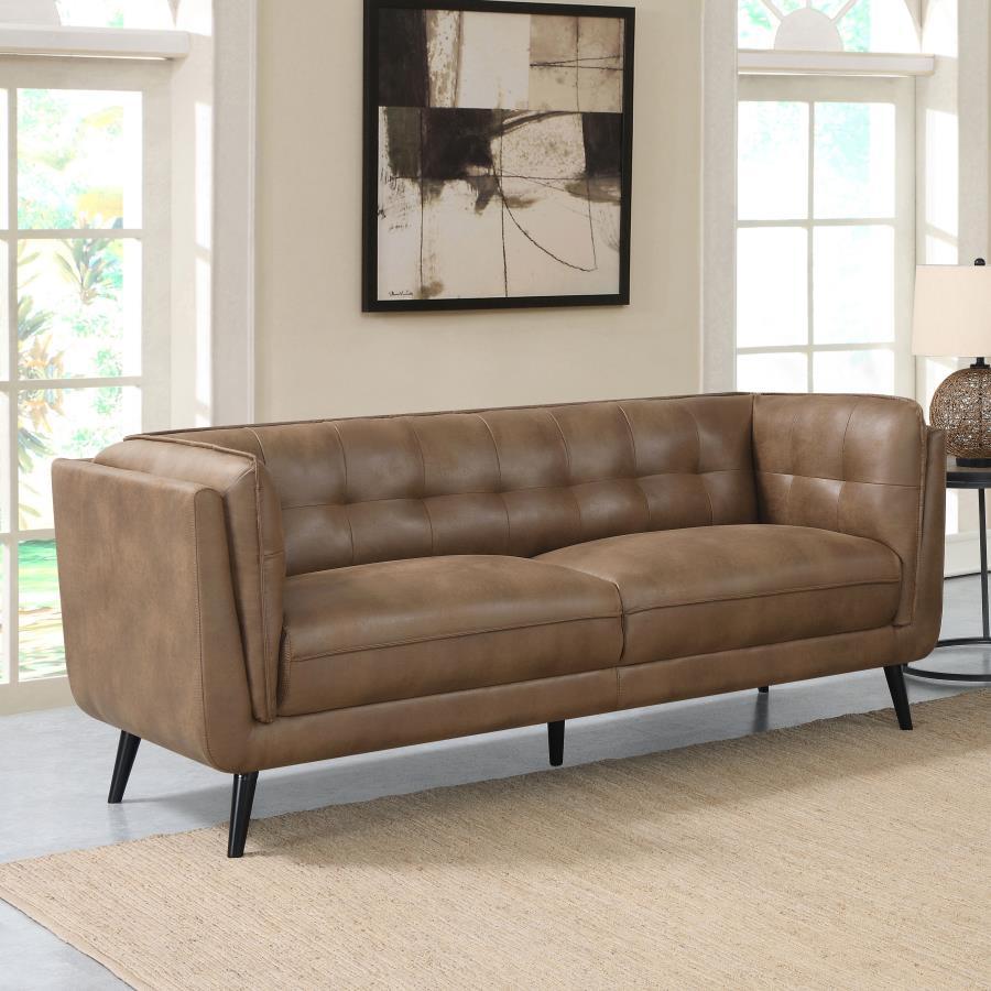 Elevate your mid-century modern living room seating area with this contemporary Chesterfield shelter style sofa, upholstered in a soft and smooth brown microfiber leather throughout its welt-trimmed and grid tufted seats and cushions. Plush and inviting w