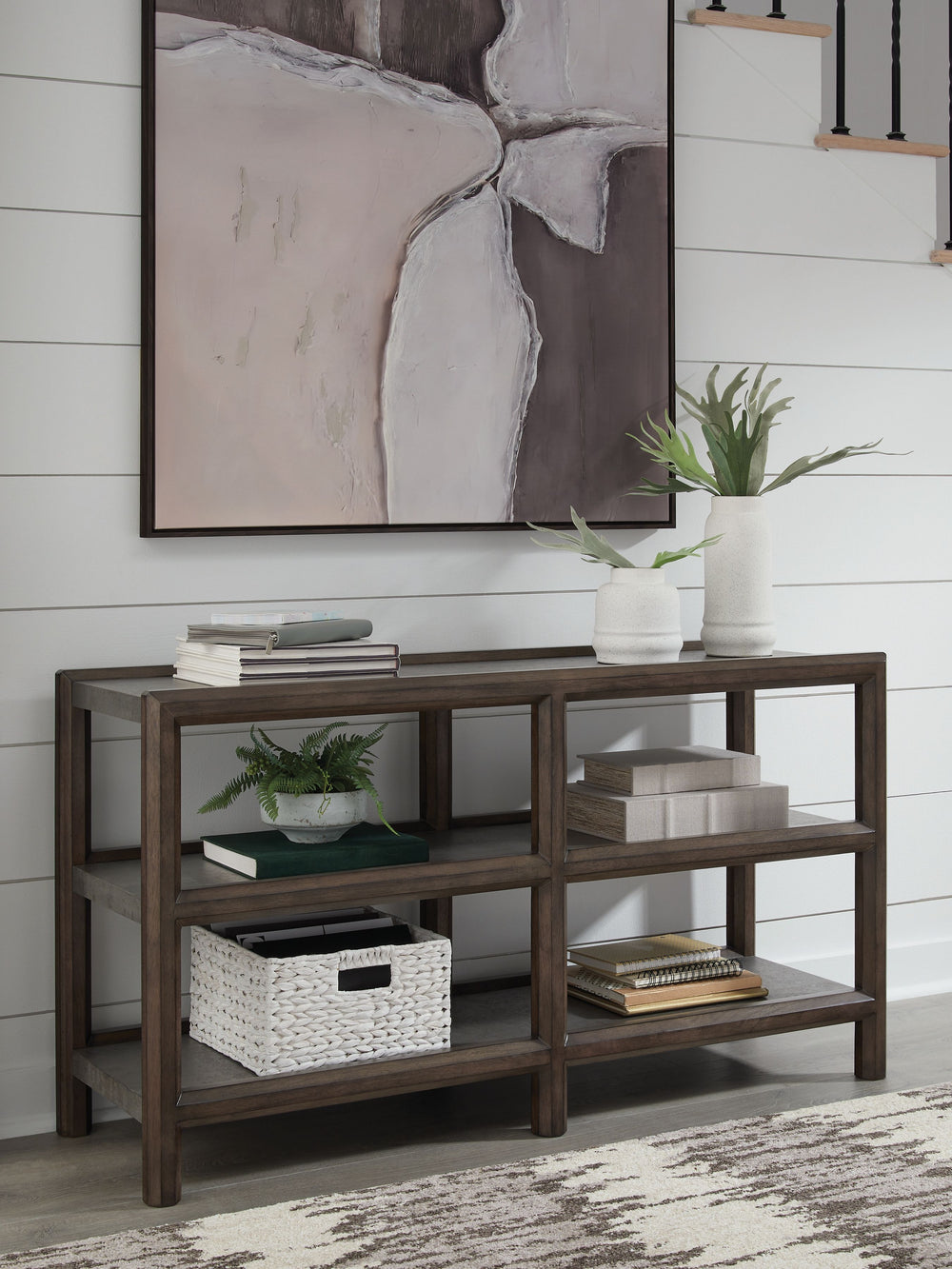 Master the art of mixed-material design with this sofa table. It sports an urban vibe, with faux cement lending an industrial edge to the contrasting dark brown finish. For a functional touch, lower shelves showcase your decor in style. Detailed mouldings