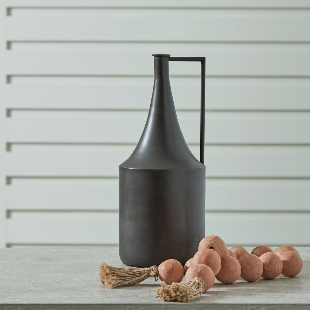 Chic on a tabletop or shelf, this vase is an eye-catching accent. Its angular handle provides a sharp, stunning geometric contrast to the curved neck. Finished in a distressed brown hue, this piece plays well in spaces ranging from casual to contemporary.