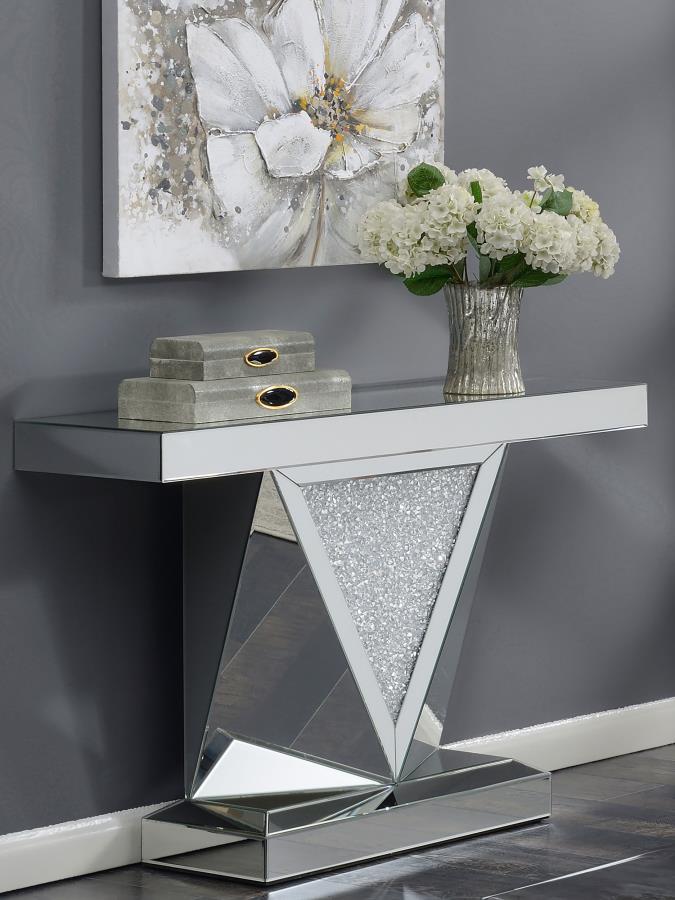 This mirrored console table features a sleek rectangular design with a bold, geometric base. The triangular inlay is adorned with acrylic crystals, enhancing its modern appeal. Made with mirrored surfaces, the console offers a sophisticated look that refl