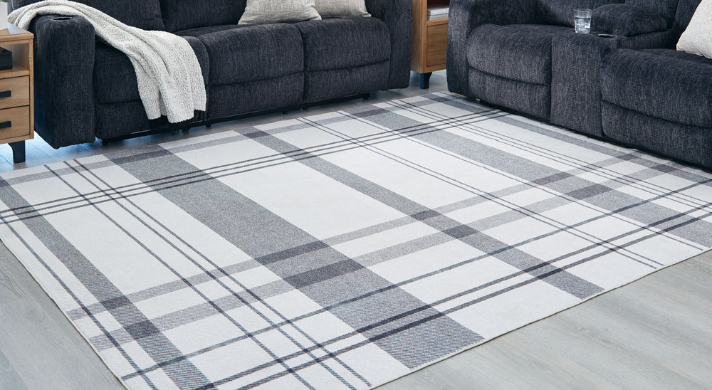 A fresh take on iconic plaid, this accent rug is both classic and contemporary. Its plaid design, with shades of gray crisscrossing against a solid cream background, has subtle variations that offer an artisanal feel. In addition, the machine woven materi