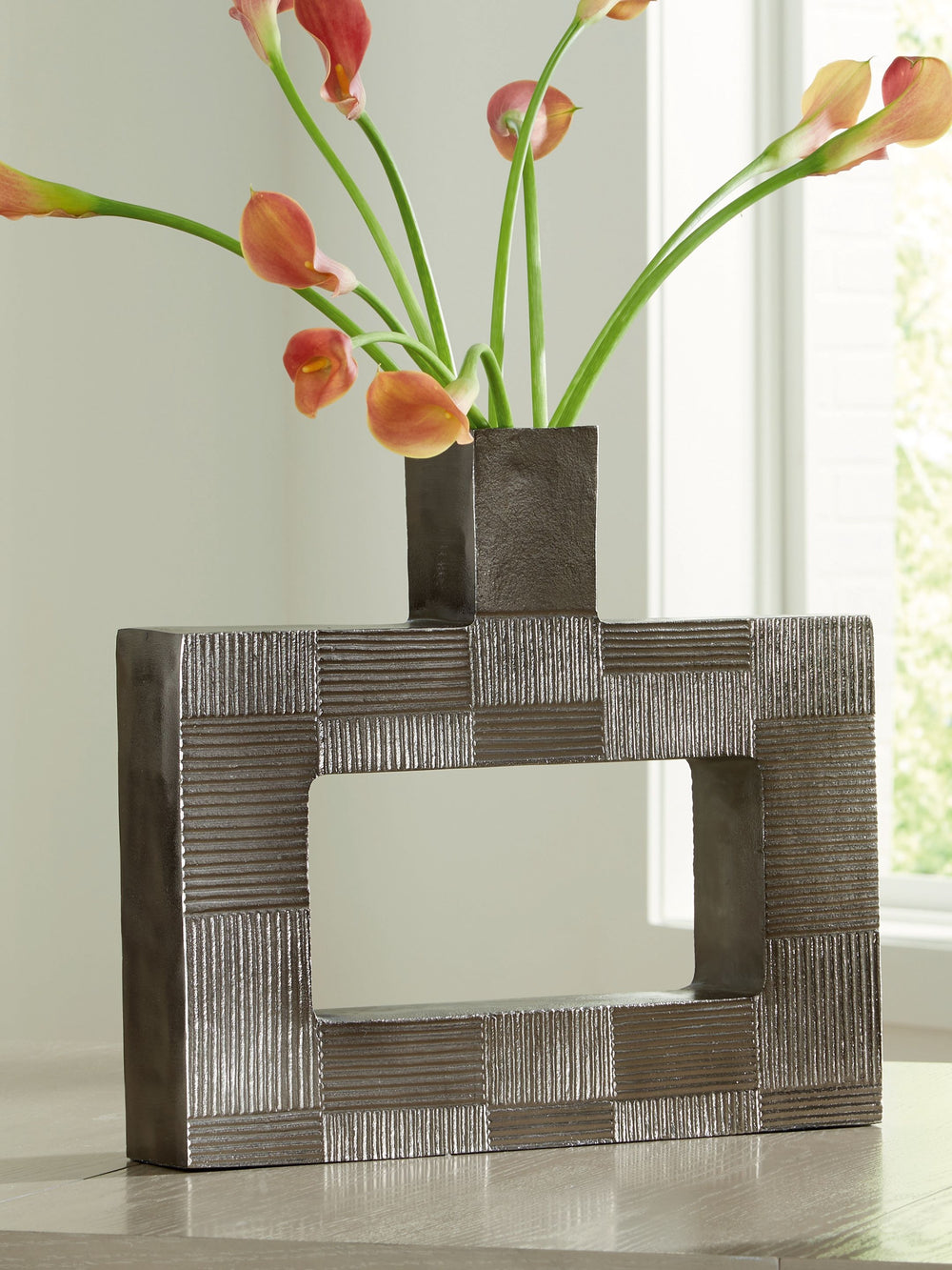 Stunning from all angles, this vase-'s contemporary geometric form acts as a captivating focal point for your mantle or bookshelf. Its antiqued nickel-tone body is detailed with subtle texture for added visual appeal. What a perfect fit for those seeking 