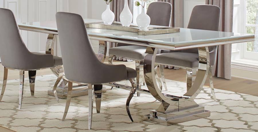 This modern dining table makes a bold statement with its sleek tempered glass top and sculptural stainless steel base. Designed for both elegance and durability, the spacious rectangular surface provides ample room for dining, while the curved trestle des