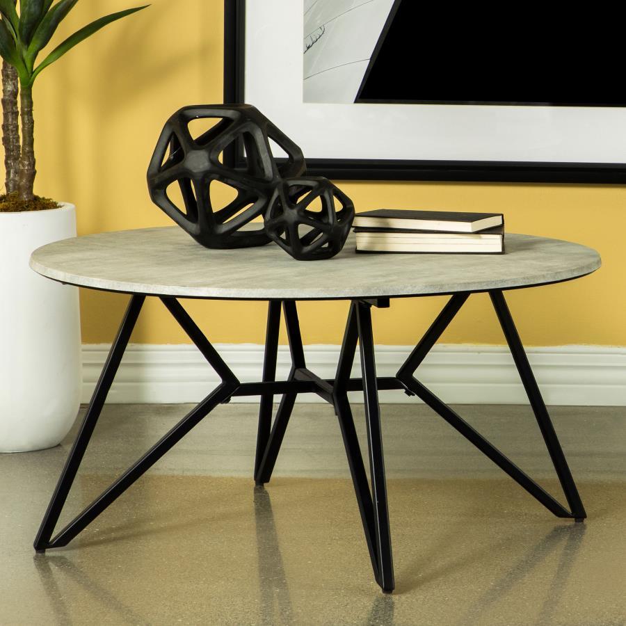 Gunmetal finish hairpin legs offer an industrial edginess to this modern coffee table. Designed with a faux cement top in an elegant round shape, this spacious cocktail table offers a casual, chic space to keep books, cocktails and more. The cement-like t