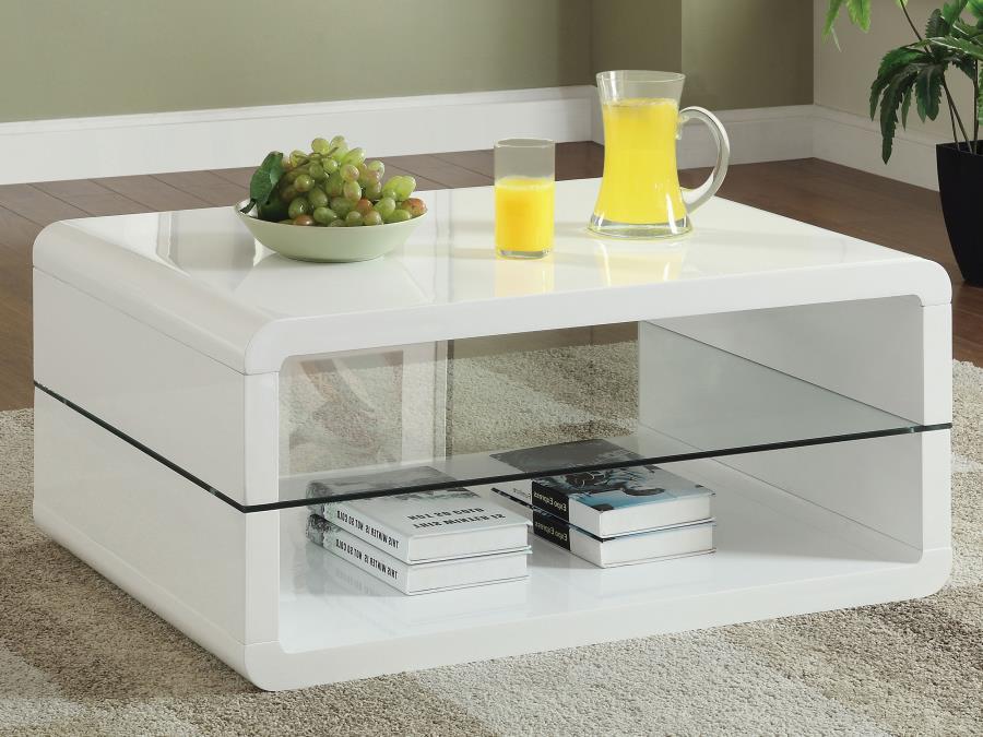 This ultra-modern rectangular coffee table combines a sleek white high-gloss finish with the sophistication of clear tempered glass. Crafted from engineered wood, its smooth, curved edges add a contemporary appeal, while the integrated glass shelf provide