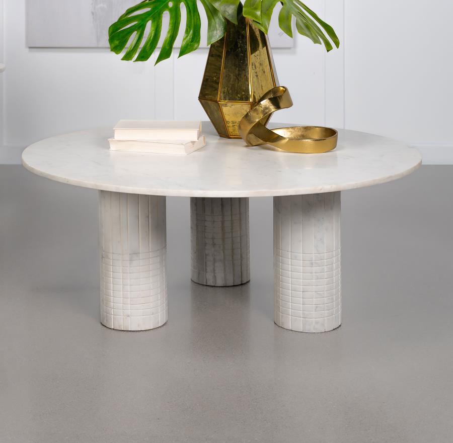 Amidst the gentle hum of daily life, this coffee table, crafted from genuine white marble, commands attention with its avant-garde design. Its round top rests on three cylindrical pedestals, each adorned with subtle grid-textured detailing. Blending the t