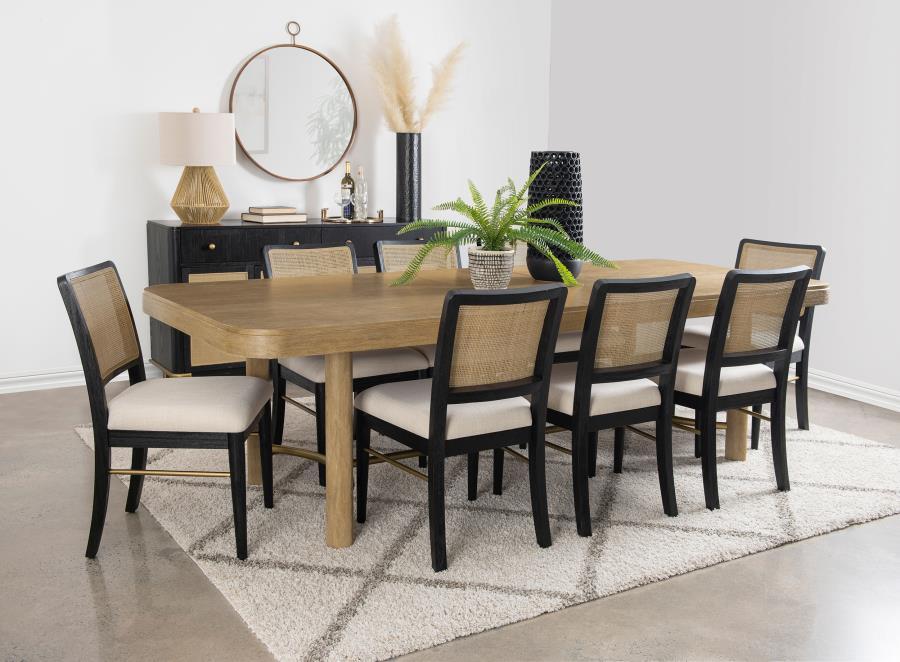 This dining set blends modern craftsmanship with natural textures for a refined yet inviting feel. The dining table features a trestle base with an antique brass-finished metal stretcher bar, adding stability and contrast. Rounded corners soften the recta