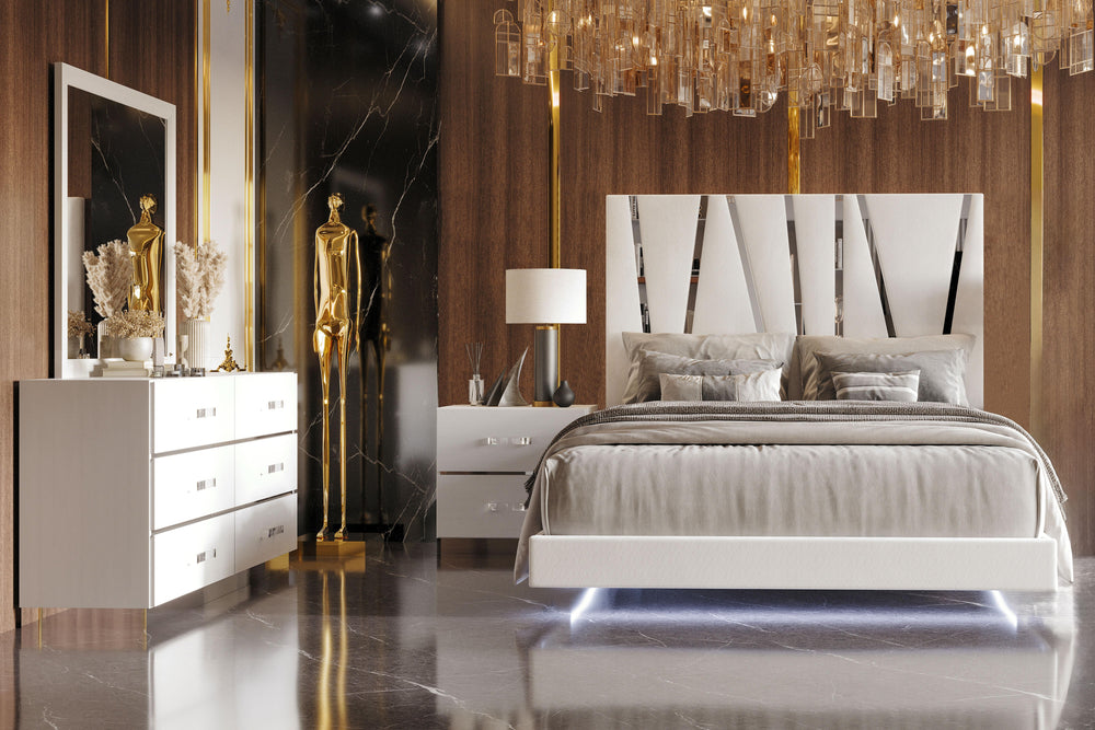 The Europa 4 Piece Bedroom Set in white is the epitome of modern elegance and practical design. This set includes a panel bed along with a dresser, mirror, and nightstand. The sleek, sophisticated look is achieved through a majestic headboard, glossy whit