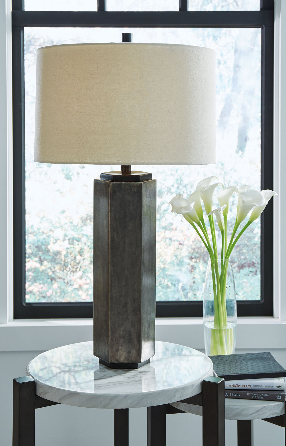Why settle for standard light fixtures when this table lamp adds so much warmth and style? This hexagon-shaped lamp features an antiqued pewter-tone and black finish topped with a drum shade. Whether lighting a living area, bedroom or entryway, this piece