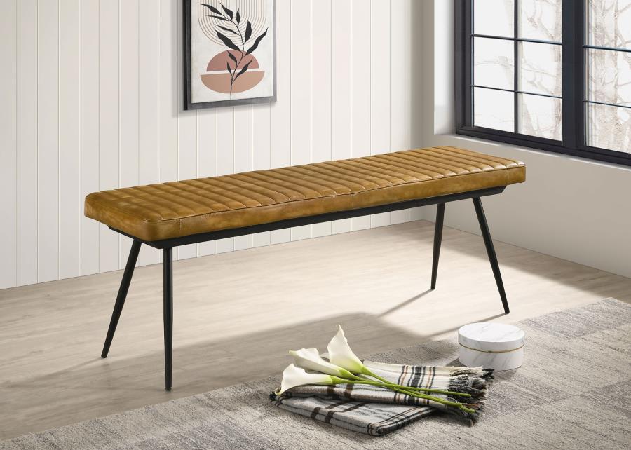 Blending rustic charm with industrial appeal, this dining bench is a bold yet versatile seating option. Upholstered in hand-dyed genuine goat leather, the padded seat with vertical tufting offers both comfort and durability. The sleek black metal base, fe