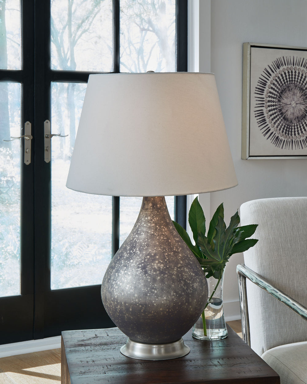 Distressed glass gives this table lamp an industrial look, while the traditional silhouette keeps it classic. Crafted of mercury glass, its urn-shaped body and free-form antiqued finish convey a vintage aesthetic. An empire shade enhances the designâ€™s t