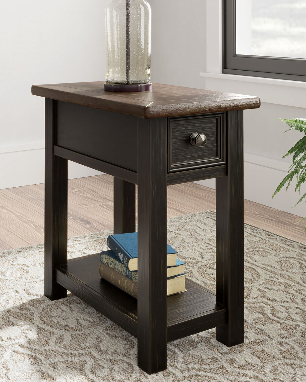 Quality crafted and richly styled, this rectangular chairside end table is sure to charm. Its two-tone aesthetic pairs a weathered grayish brown tabletop with a textured wire brushed base in black. A built-in shelf offers handy display space. And the tabl