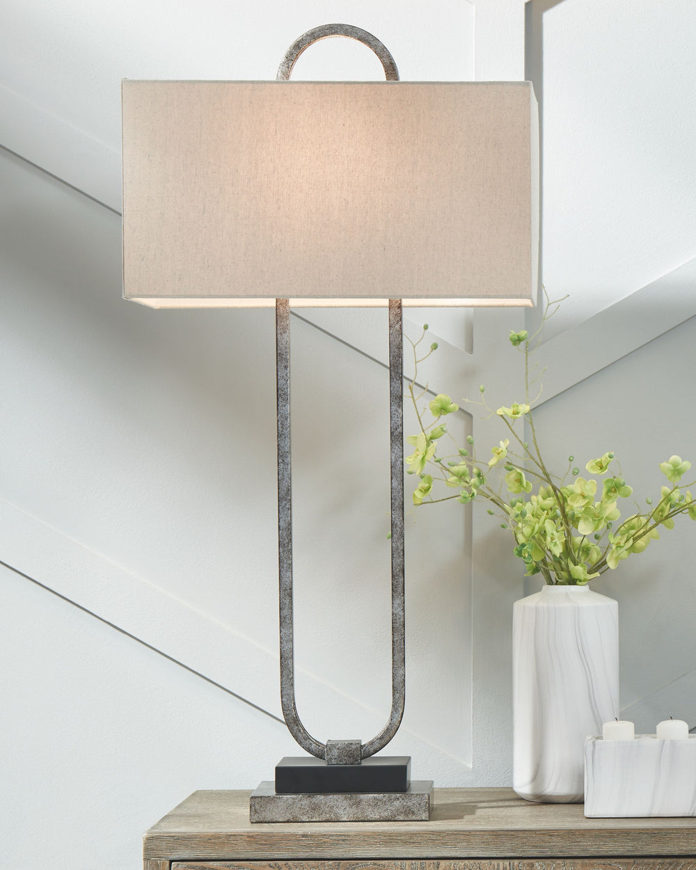 This table lamp, with its open, geometric design, draws the eye and is visually stunning. The antiqued silver metal body with rectangular hardback shade completes the look. This table lamp is sure to be a showpiece wherever you use it.<br><br><b>Additiona