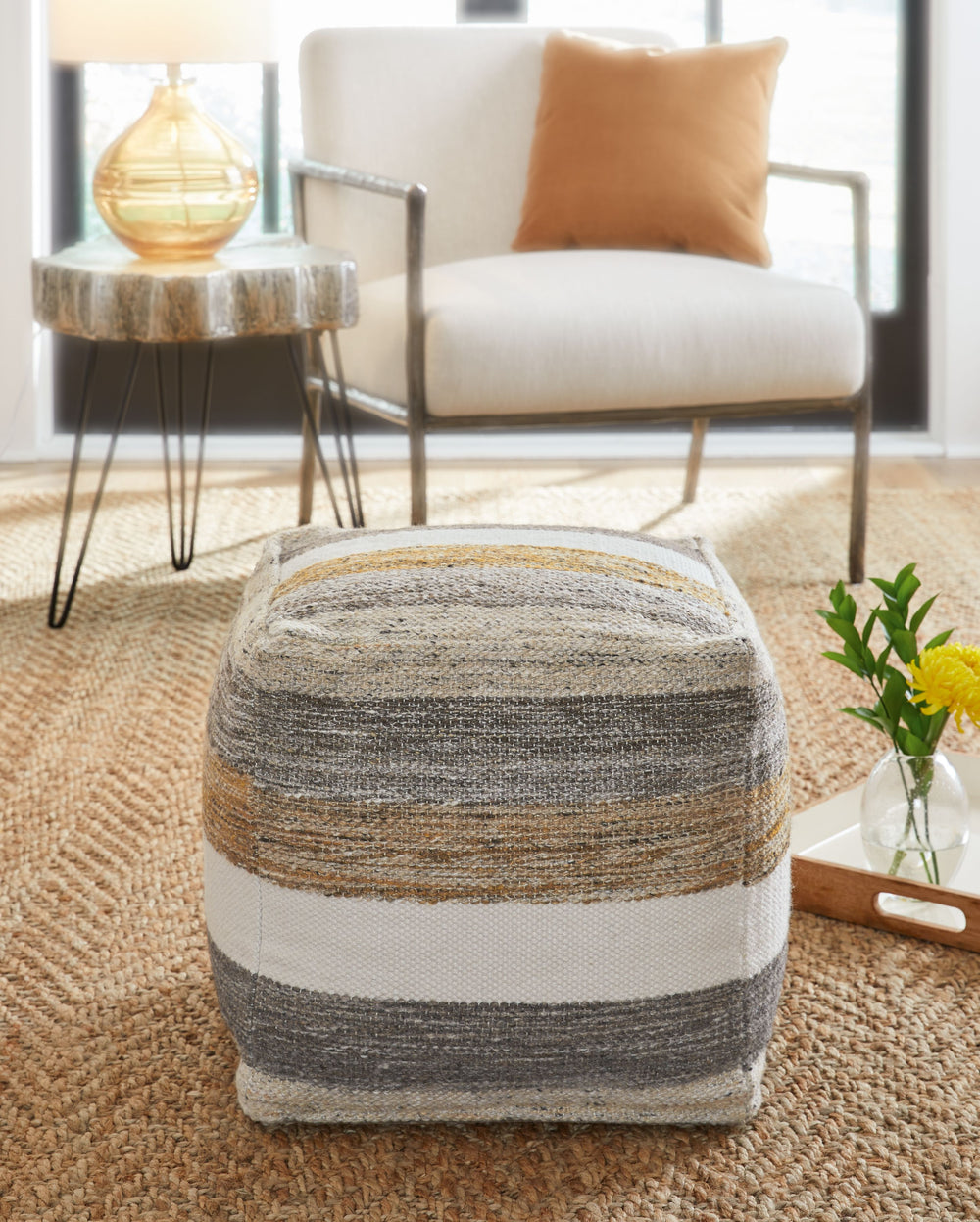 Weaving together stripes in grounded, earthy tones, this pouf is a natural beauty. It combines simple flair and function, with hues of white, honey and shades of gray and brown to keep things casual. Whether used as a footrest or a side table, this piece 