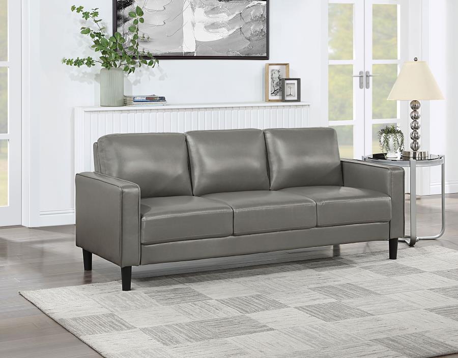 Establish the foundation of a stylish living room with a modern sofa. Smooth faux leather creates a sleek, neutral look that brims with sophistication. Track arms create a structured silhouette, offering tailored flair with an understated ambiance. Straig