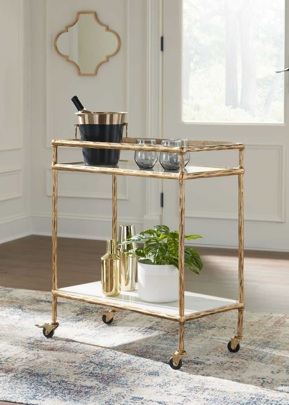 Store and serve in sleek style with this bar cart. Its casually cool design combines an antiqued brass-tone frame with white marble and clear glass. Rails on the top shelf help bottles and shakers stay organized. And with its rolling casters, you can make