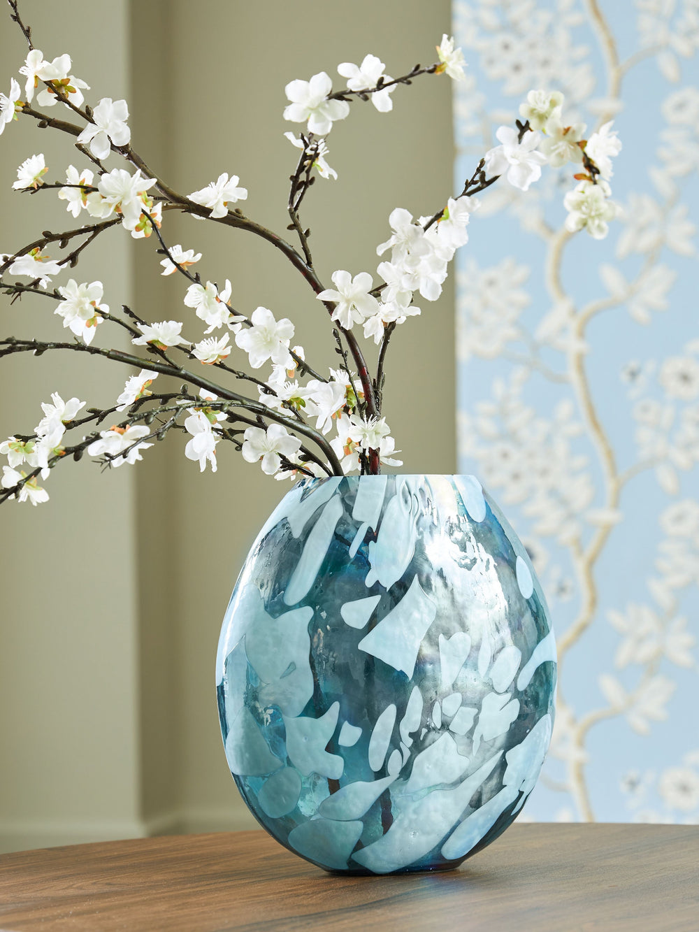 Display florals in captivating contemporary style with this vase. Iridescent details and shades of teal marry to make an artful interpretation of color. Whether it-'s showing off seasonal blooms or standing alone, this piece is a graceful addition to your