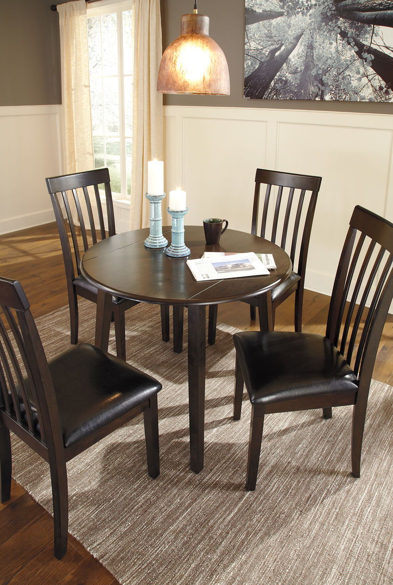 Made with select birch veneer and hardwood solids in a transitional dark brown finish with gray undertones. Compact table seats four and includes drop leaves for multi-function. <h4><b>Hammis - Dark Brown - Round DRM Drop Leaf Table</b></h4> <table width=
