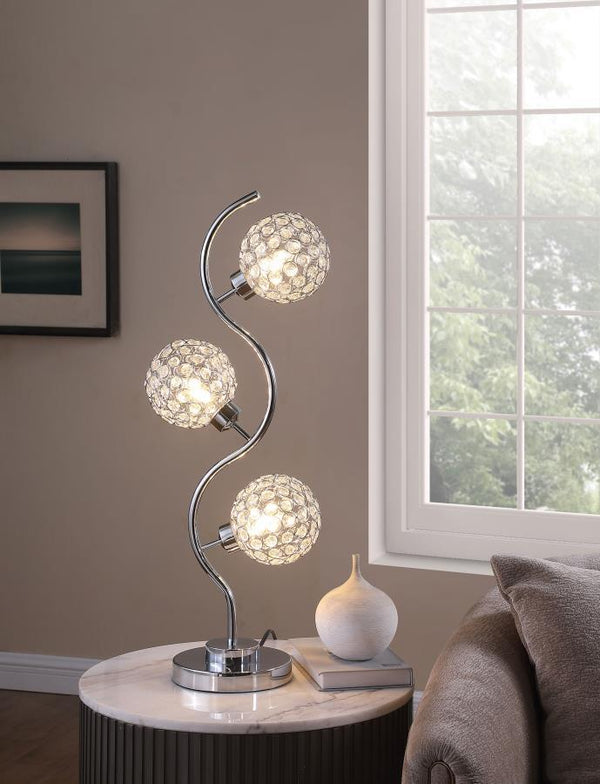  this modern three-light table lamp is a superb choice for a sophisticated living space. A corkscrew inspired post gleams in a chrome finish and hosts its three lights. Each features an orb shade dotted with crystal-like embellishme