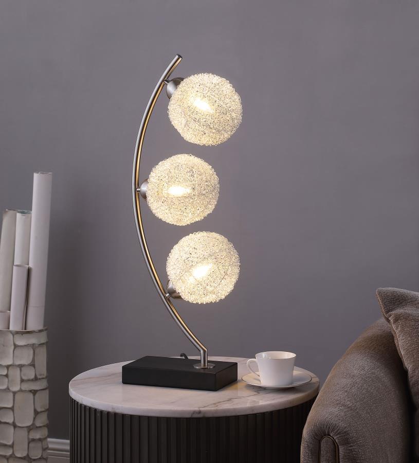 Graceful silhouetting pairs with a trio of elegant wire frame orb shades in a modern table lamp. Designed to make an impact on a console or side table, it features a fresh, modern look complete with a vertical arc frame in a chrome finish. The arc hosts t