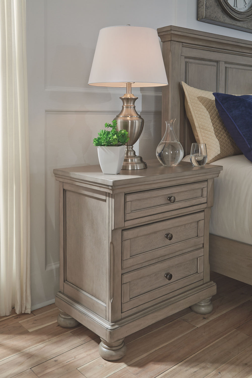 Satisfying your taste for tradition, this nightstand sports serene sophistication. Forever classic design detailsâ€”inlaid panels, silvertone patina hardware and bun feetâ€”are so easy to love. Its burnished light gray finish elevates the look with modern