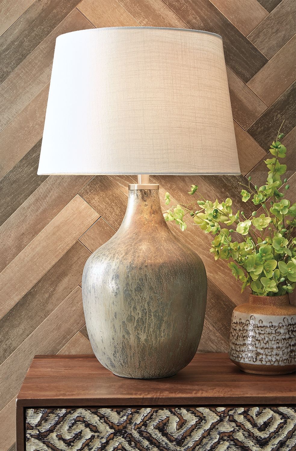 Evoke a vintage vibe in a thoroughly modern way with this glass table lamp. The gray-blue and light goldtone of the mercury-glass finish reflects a primitive aesthetic juxtaposed with the contemporary jar shape of this lamp. Add texture, interest and a ce