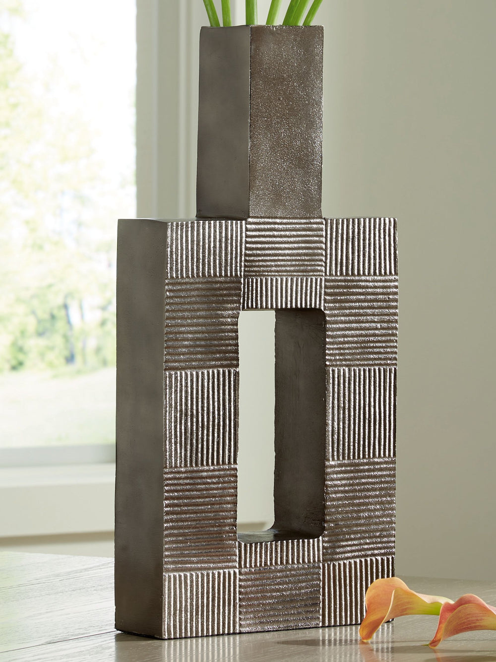 Stunning from all angles, this vase-'s contemporary geometric form acts as a captivating focal point for your mantle or bookshelf. Its antiqued nickel-tone body is detailed with subtle texture for added visual appeal. What a perfect fit for those seeking 