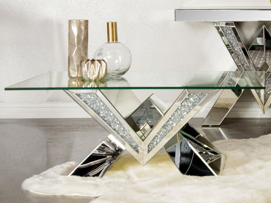 This mirrored coffee table serves as a stunning centerpiece with its bold design. The V-shaped base showcases mirrored panels and sparkling crystal accents for an opulent look. The rectangular, beveled tempered glass top adds elegance and practicality, ma