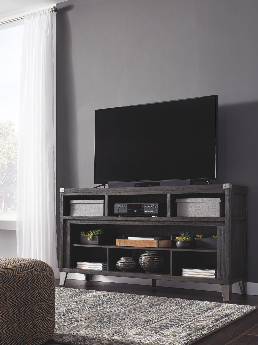 Make watching TV a joy. This TV stand-'s rustic-industrial styleâ€”with a gray finish, squared edges, zinc-tone corner bracket accents and nailhead detailingâ€”is sure to complement any contemporary decor. Several vented open cubbies offer impressive shel