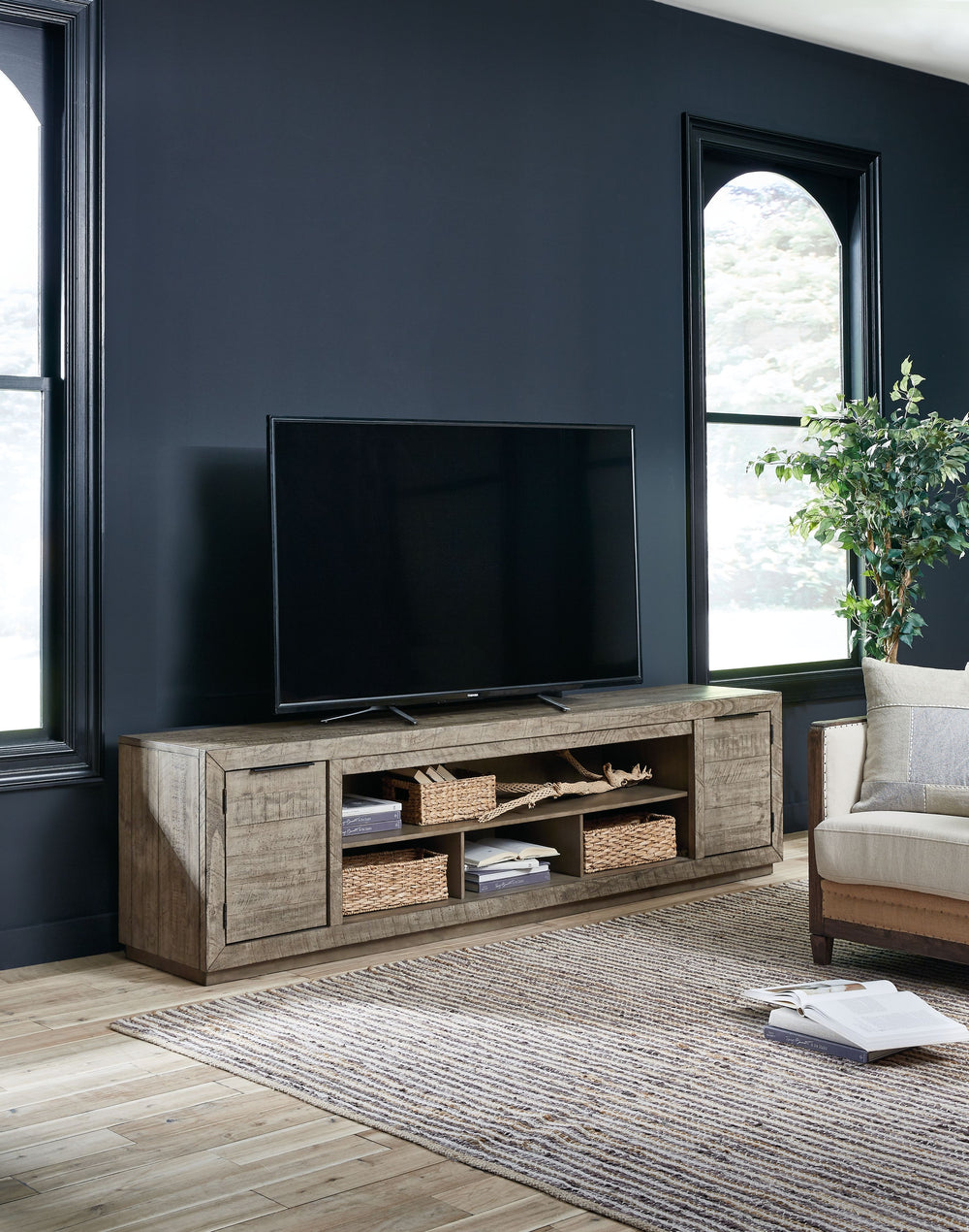 This extra-large TV stand is sure to win your heart with its daring take on modern rustic expression. Its crisp, clean minimalist-chic profile is enriched with striking pine wood grain and a weathered gray finish with distressed saw mark texture. Designed