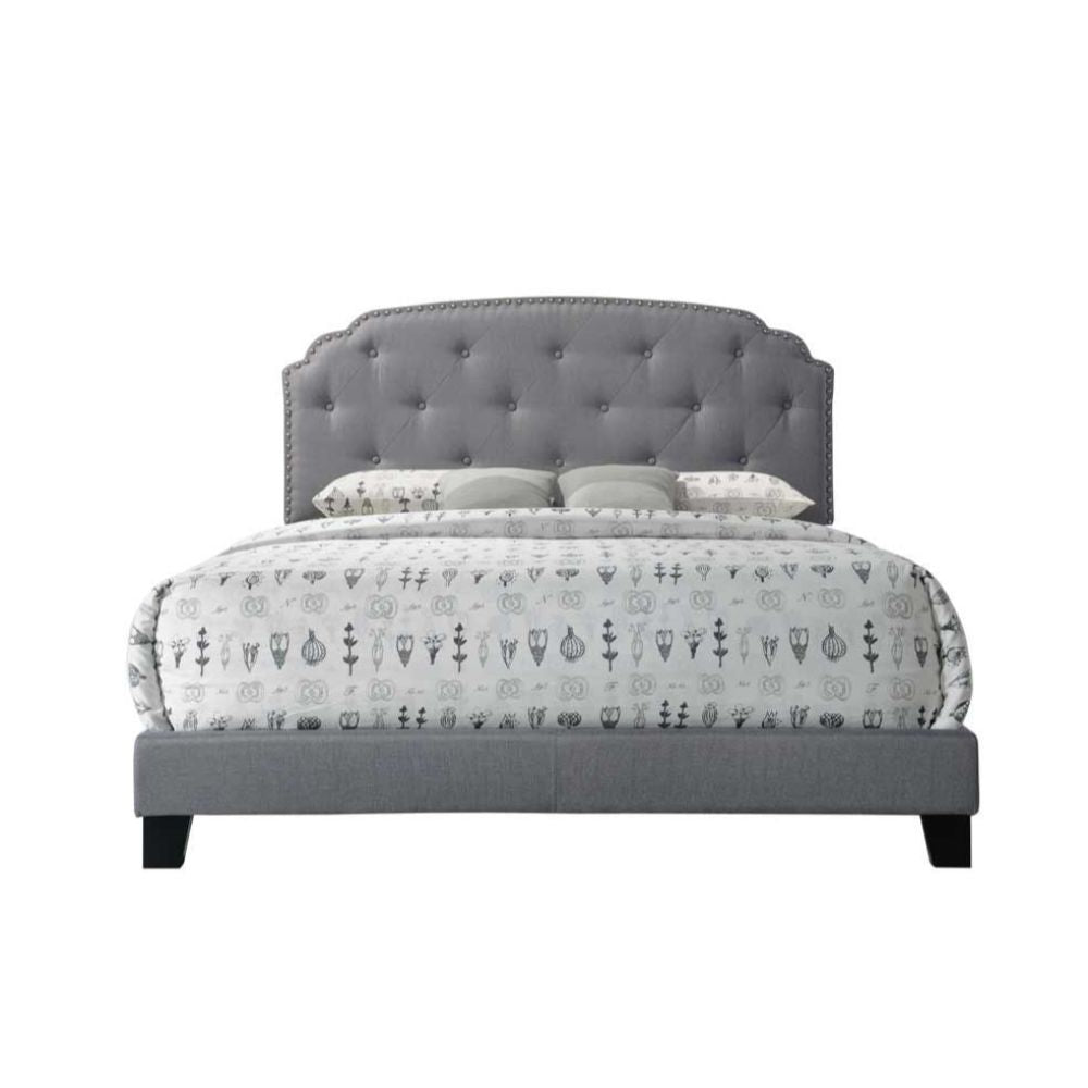 The Tradilla queen bed is a platform style bed featuring padded fabric on the headboard, footboard and side rails. It is supported by wood feet and wood headboard posts. The headboard features Nailhead trim bordering an interesting traditional top shape, 