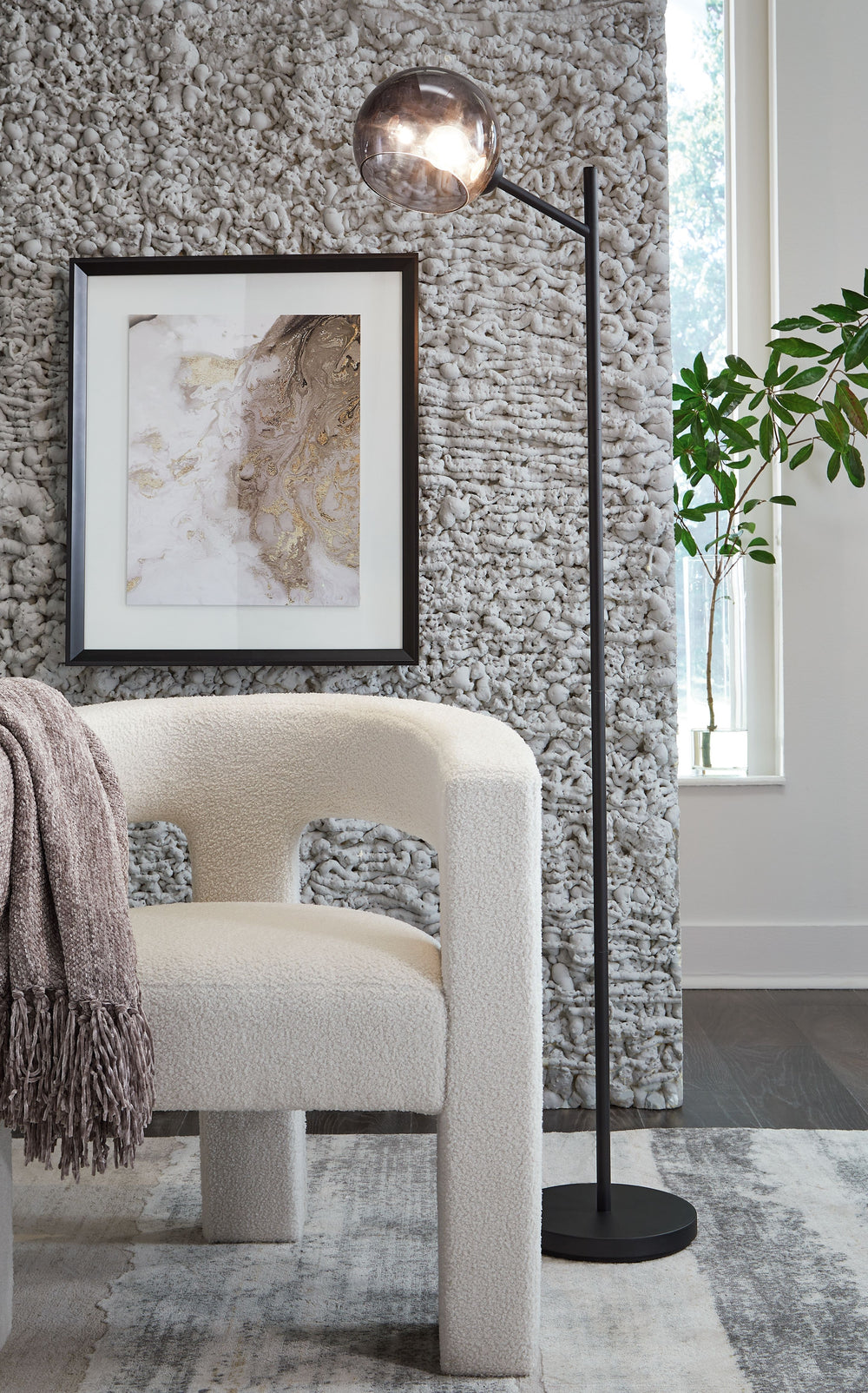 This floor lamp is designed to shine light where you need it most without compromising on style. Its contemporary black finish pairs well with neutrals or pops of color, while the smoky glass shade brings a fresh take to the look. The lamp is a smart addi