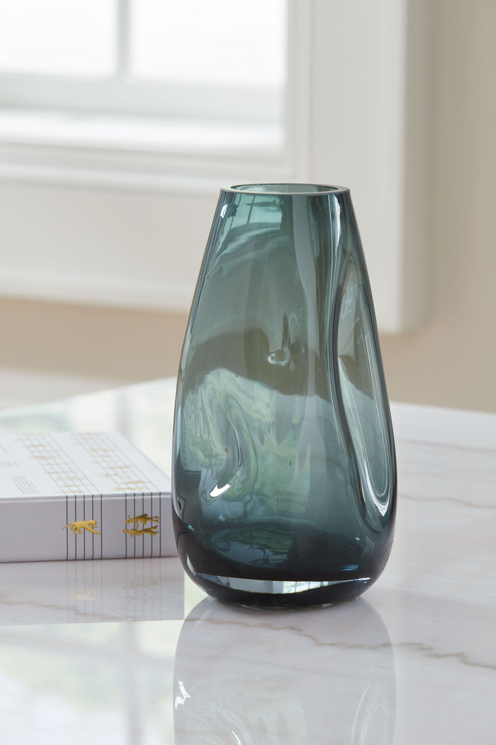 Sleek. Contemporary. Chic. This vase has an organic sense of movement, recalling seaside aesthetics with its teal glass. A stunning solo accent, it also acts as a beautiful vessel for florals and other decorative fillers. And the vase is safe for outdoor 