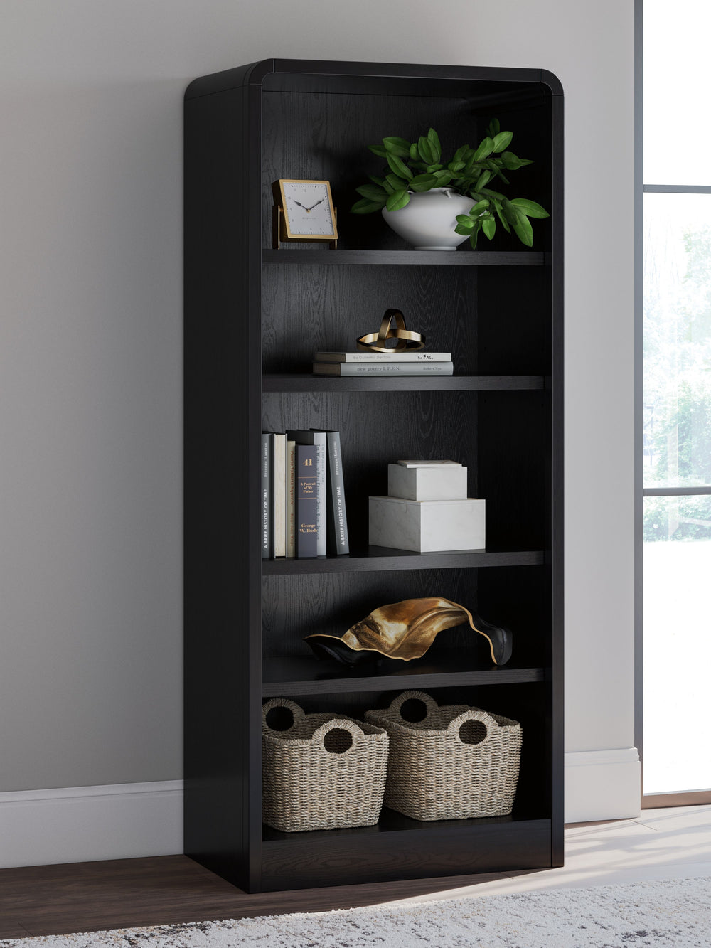 Inspired by art deco design, this softly shaped bookcase makes a lasting impression in a simply stunning way. Its magnificent curved silhouette is enhanced by a rich layered black finish on the textured wood grain surface. Complete with shelves to display