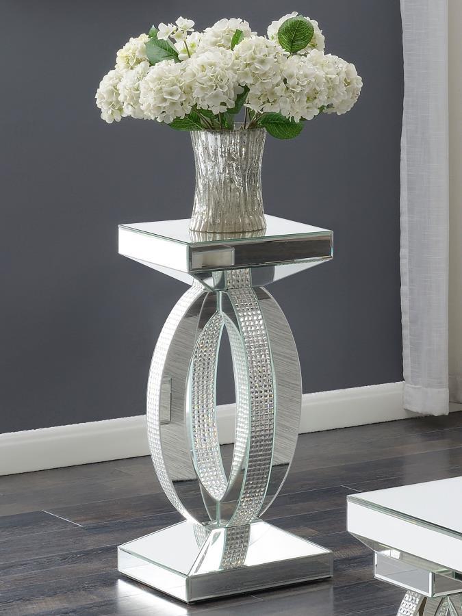 This chic and contemporary end table captivates with its sculptural, artistic design. Crafted with mirrored surfaces and engineered wood, it exudes modern luxury. The intersecting oval-shaped loops form a striking, three-dimensional silhouette, enhanced b